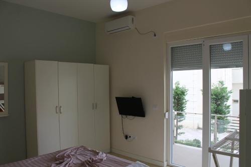 a bedroom with a bed and a tv and a cabinet at Blue Apartments & Hotel Shengjin in Shëngjin