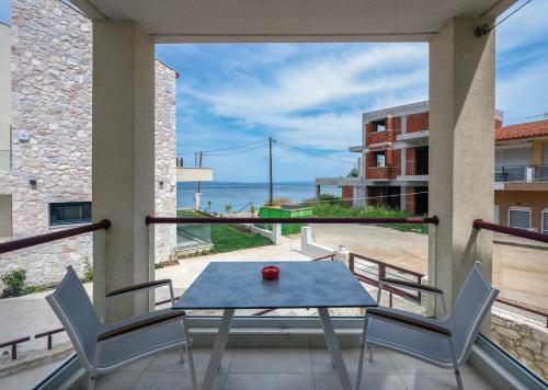 balcón con mesa, sillas y vistas al océano en Elpiniki Luxury Rooms, en Nea Potidaea
