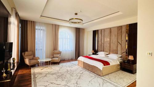 ein Schlafzimmer mit einem Bett und Stühlen in einem Zimmer in der Unterkunft KANGURT Grand Hotel in Duschanbe
