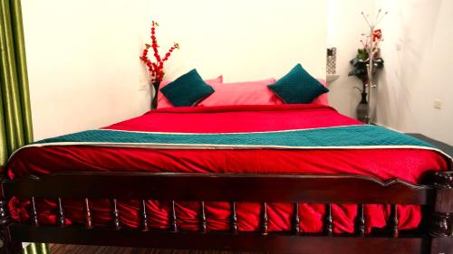 a bed with a red blanket and green pillows at Arabian Nights Munnar Pool Villa in Munnar