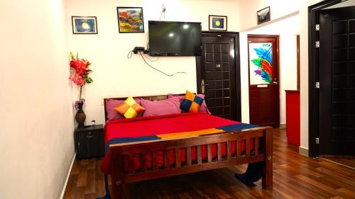 a bedroom with a bed and a tv on the wall at Arabian Nights Munnar Pool Villa in Munnar