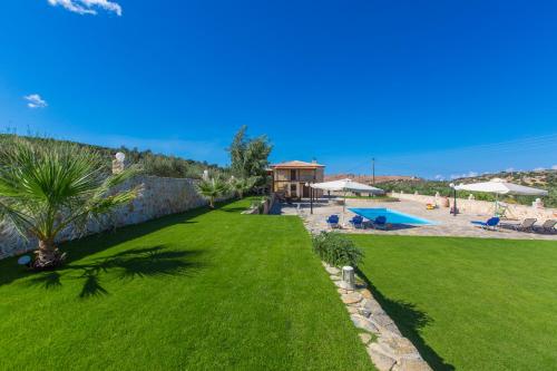 a green lawn with a swimming pool and a resort at Nestor Villa, with Private Pool & Absolute Privacy in Roumelí