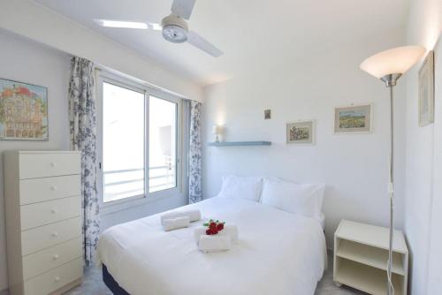 une chambre blanche avec un grand lit blanc et une fenêtre dans l'établissement PALM ROYAL - Apt for 4 with balcony - 5 minutes from the beach, à Antibes