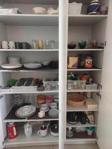 a white pantry with plates and dishes on shelves at Jaffa Getaway sea front, luxury Duplex, Port & Old City 2m walk in Tel Aviv
