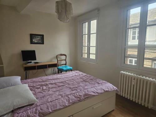 Un dormitorio con una cama y un escritorio con una computadora. en le cosy Dieppe, en Dieppe