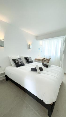 un grand lit blanc dans une chambre avec une fenêtre dans l'établissement Immersione - Clim - Terrasse Jardin - Centre ville, à Cassis