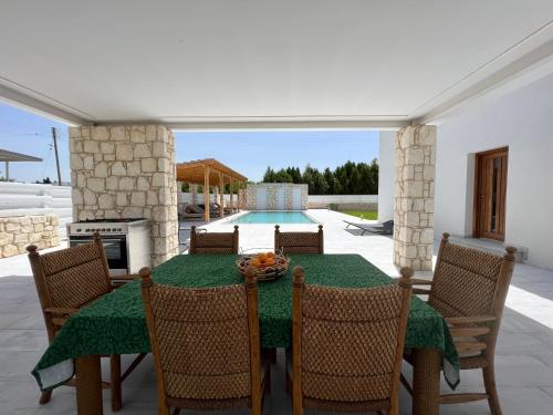a dining room with a table and chairs and a pool at First Eco-Villa in Polis Chrysochous