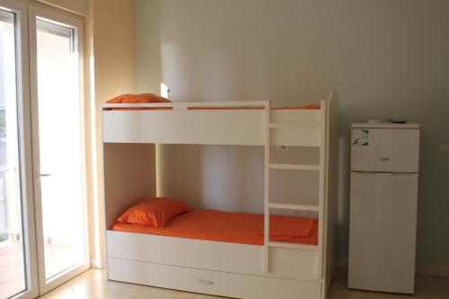 a white bunk bed with an orange pillow on it at Blue Apartments & Hotel Shengjin in Shëngjin
