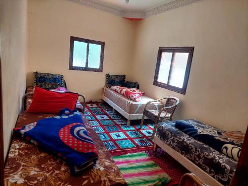 Auberge Toubkal Amsouzart Aitst Idar في Tizgui: غرفة معيشة بها سريرين وأريكة