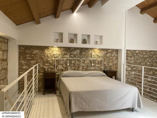 1 dormitorio con cama y pared de piedra en Tenute Plaia Agriturismo en Scopello