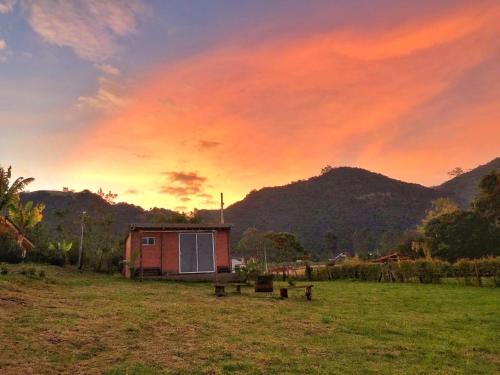 a house in a field with a sunset in the background at Refugio Aventura, romántico glamping montañero in Tabio