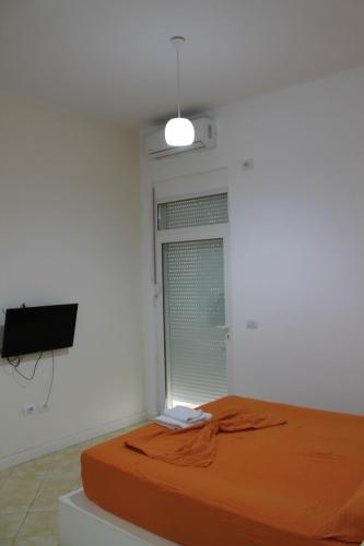 a bed in a room with a window and a television at Blue Apartments & Hotel Shengjin in Shëngjin