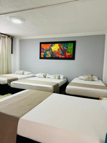 una habitación con 4 camas y un cuadro en la pared en Rey de Reyes, en Valledupar