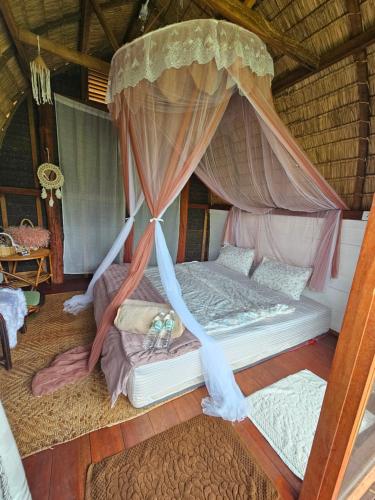 a bed with a canopy in a room at PANAKLUEA Cottage & Crafts - พนาเกลือ in Ban Kham
