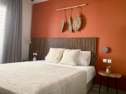 1 dormitorio con cama blanca y pared de color naranja en Αura Luxury Apartments, en Ierissos