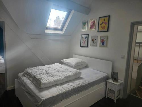une chambre blanche avec un lit et une fenêtre dans l'établissement Le Port Vauquelin, à Dieppe