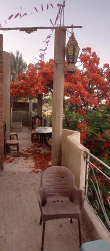 a chair sitting on a patio with red flowers at Quiet house on the Nile River in Aţ Ţarfāyah