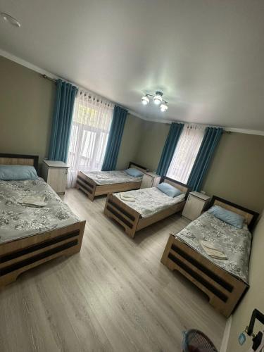 drie bedden in een kamer met blauwe gordijnen bij Aida guest house in Arkit
