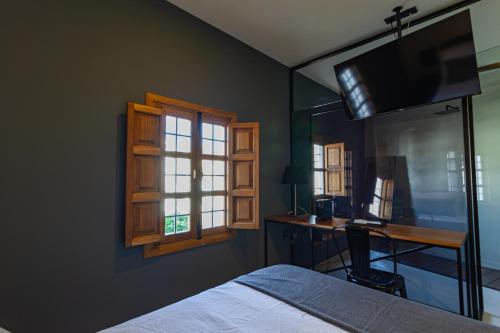 a bedroom with a bed and a desk and a window at La Casa del Conde - Un alojamiento único en Écija in Écija