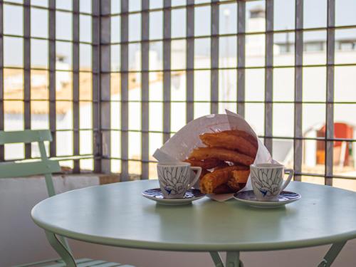 a table with a plate of bread and two cups at La Casa del Conde - Un alojamiento único en Écija in Écija