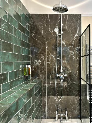 a bathroom with a shower with green tiles at St Johns Jailhouse by the Castle in Stirling