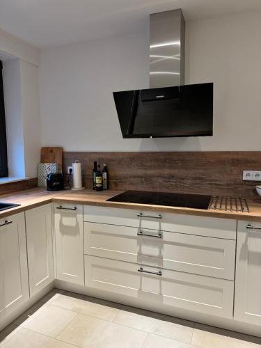 a kitchen with white cabinets and a stove top oven at Ferienhaus Zipfelstube in Selfkant
