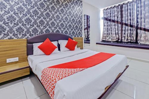 a bedroom with a bed with red pillows at Hotel Shiv Inn in Vadodara