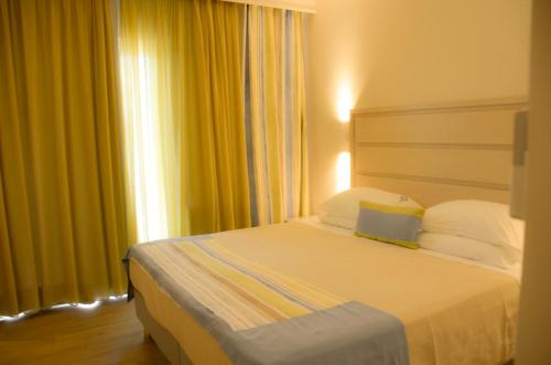 a hotel room with a bed with yellow curtains at Odysseus Hotel in Paleokastritsa
