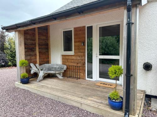 a porch of a house with a bench and potted plants at Antlers Rest in Borve