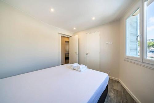un lit blanc dans une chambre avec une fenêtre dans l'établissement Centre ville Croisette, à Cannes