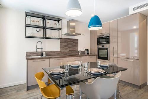 une cuisine avec une table en verre et des chaises jaunes dans l'établissement Centre ville Croisette, à Cannes