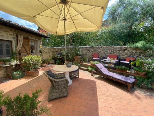 a patio with a table and chairs and an umbrella at La Magione dei Todaro in Borgo a Buggiano