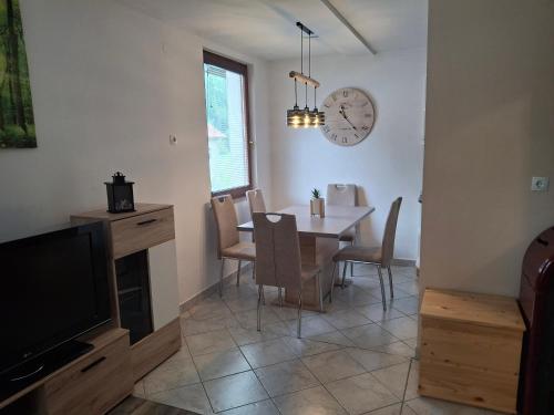 een eetkamer met een tafel en een klok aan de muur bij Apartment Veninsek in Luče