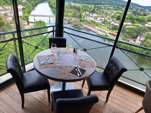 een eetkamer met een tafel en stoelen en een groot raam bij Hôtel Bellevue in Puy-lʼÉvêque