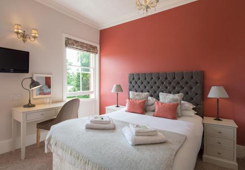 a bedroom with a large bed with red walls at Bartley Lodge Hotel in Lyndhurst