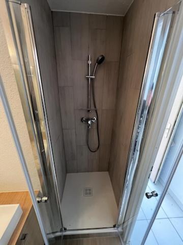 La salle de bains est pourvue d'une cabine de douche avec un pommeau de douche. dans l'établissement Zenitude Corniche charmant studio cabine vue mer, à Sète