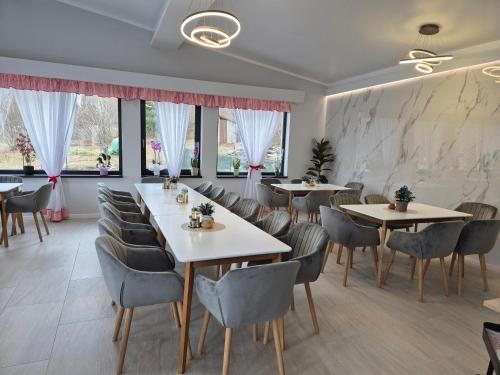 a restaurant with tables and chairs and windows at Holiday Village Tarcau in Tarcău-Gheuca