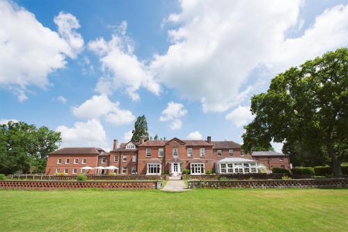 a large red brick building with a grass field at Bartley Lodge Hotel in Lyndhurst