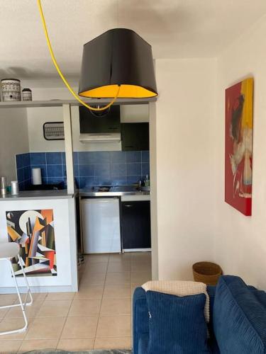 a living room with a blue couch and a kitchen at L'Entre 2 Mers avec piscine in Montech