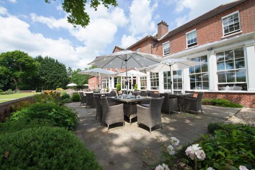 a patio with a table with chairs and umbrellas at Bartley Lodge Hotel in Lyndhurst