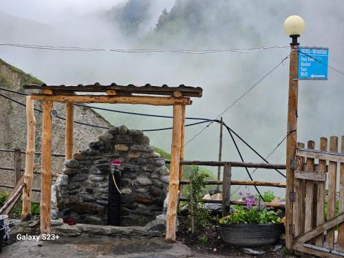 a stone fireplace in a garden with a wooden fence at MURQVAMI Guesthouse in Adishi