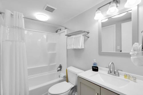 a white bathroom with a toilet and a sink at Aruba - Downtown Waterfront 2x2 Dock & Pool Pet-Friendly in Key West