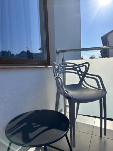 a chair sitting next to a table and a window at Willa Ada Pokoje & Apartamenty in Karwia