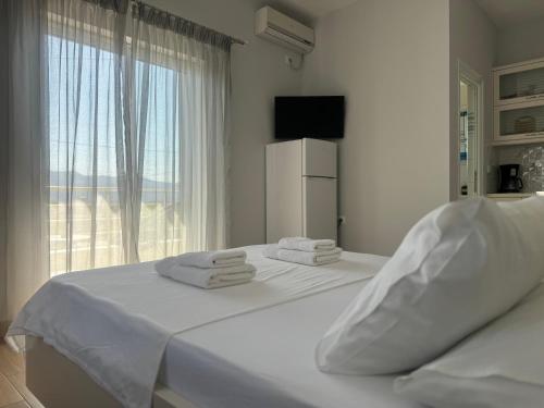 um quarto com 2 camas com lençóis brancos e uma janela em Villa Almando em Ksamil