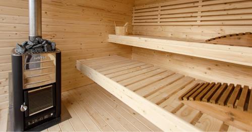 a wooden sauna with a stove and two beds at Holiday Village Tarcau in Tarcău-Gheuca