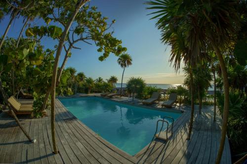 une piscine avec des palmiers et une terrasse en bois dans l'établissement Hotel Poc Na Tulum, à Tulum