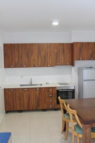 a kitchen with wooden cabinets and a wooden table at Blue Apartments & Hotel Shengjin in Shëngjin