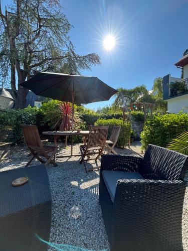 a patio with a table and chairs and an umbrella at Chambres Dhôtes Numéro 1 in Châteaulin