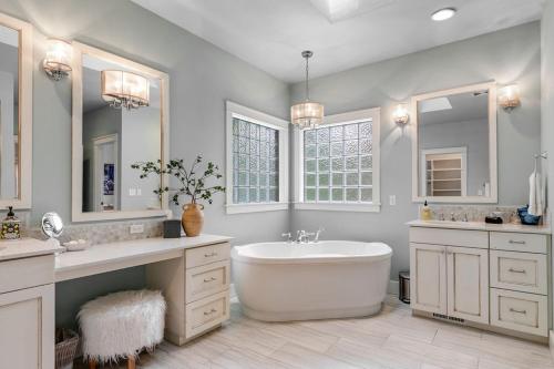 a white bathroom with a tub and a sink and mirrors at Spacious Eagle Home with Hot Tub in Eagle