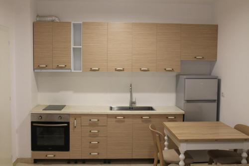 a kitchen with wooden cabinets and a table and a sink at Blue Apartments & Hotel Shengjin in Shëngjin